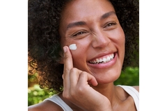 Woman putting moisturizer on her cheek.